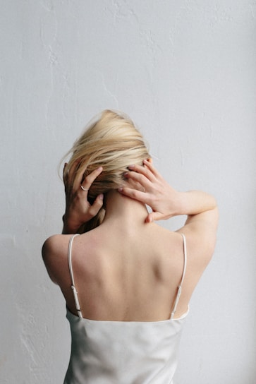 woman in white spaghetti strap top covering her face