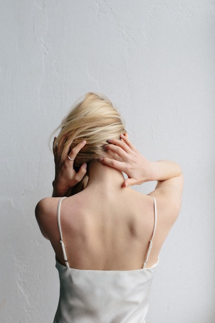 woman in white spaghetti strap top covering her face