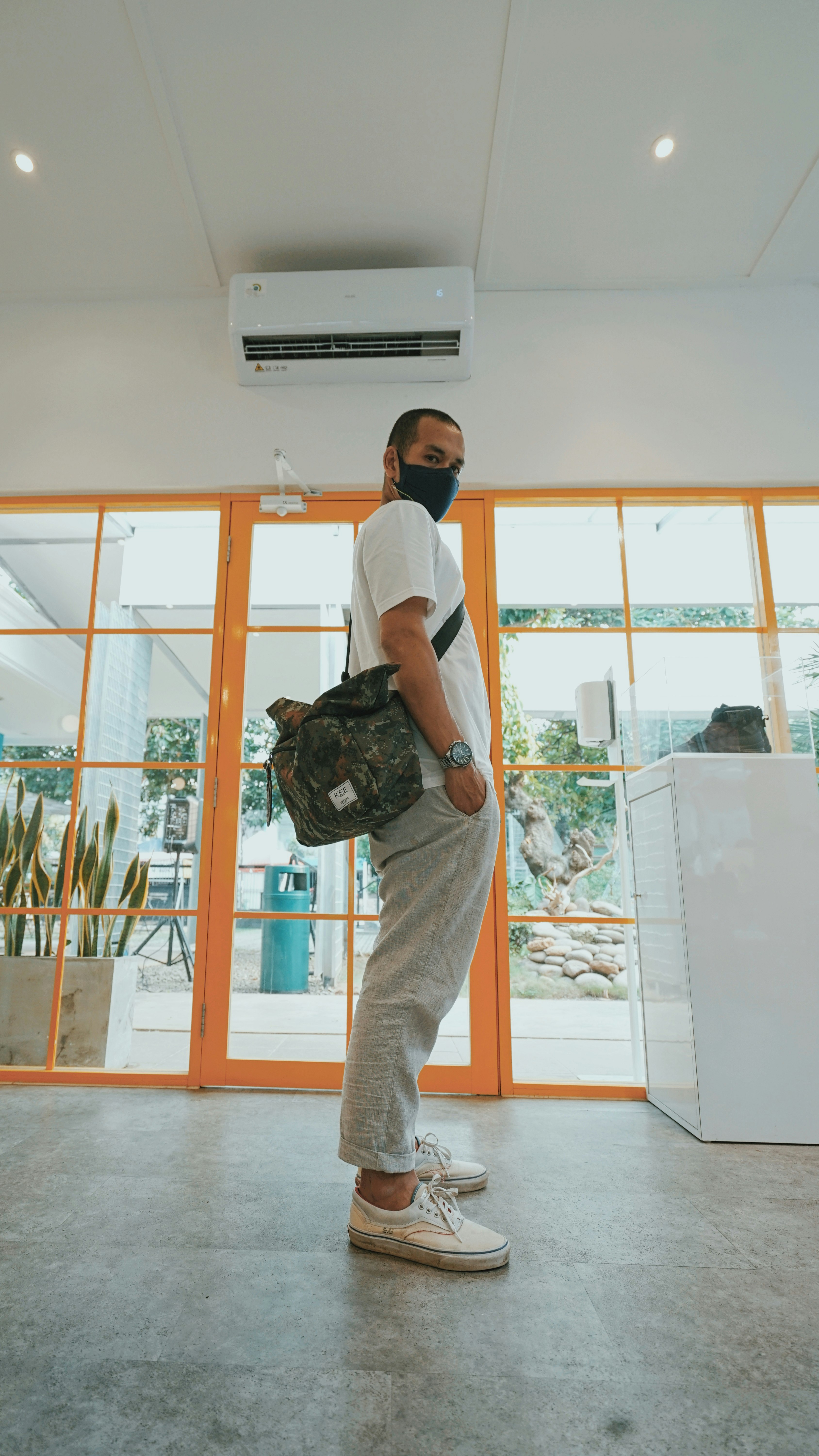 man in white t-shirt and beige pants carrying black backpack