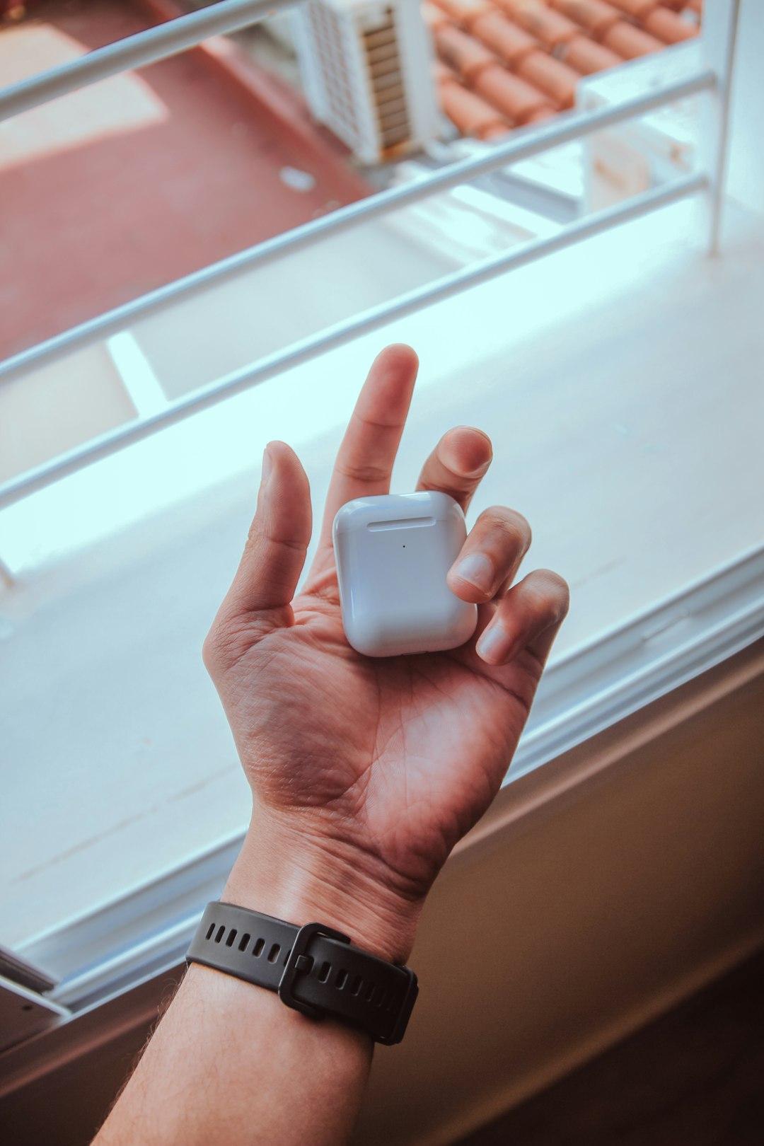 person holding white apple airpods charging case
