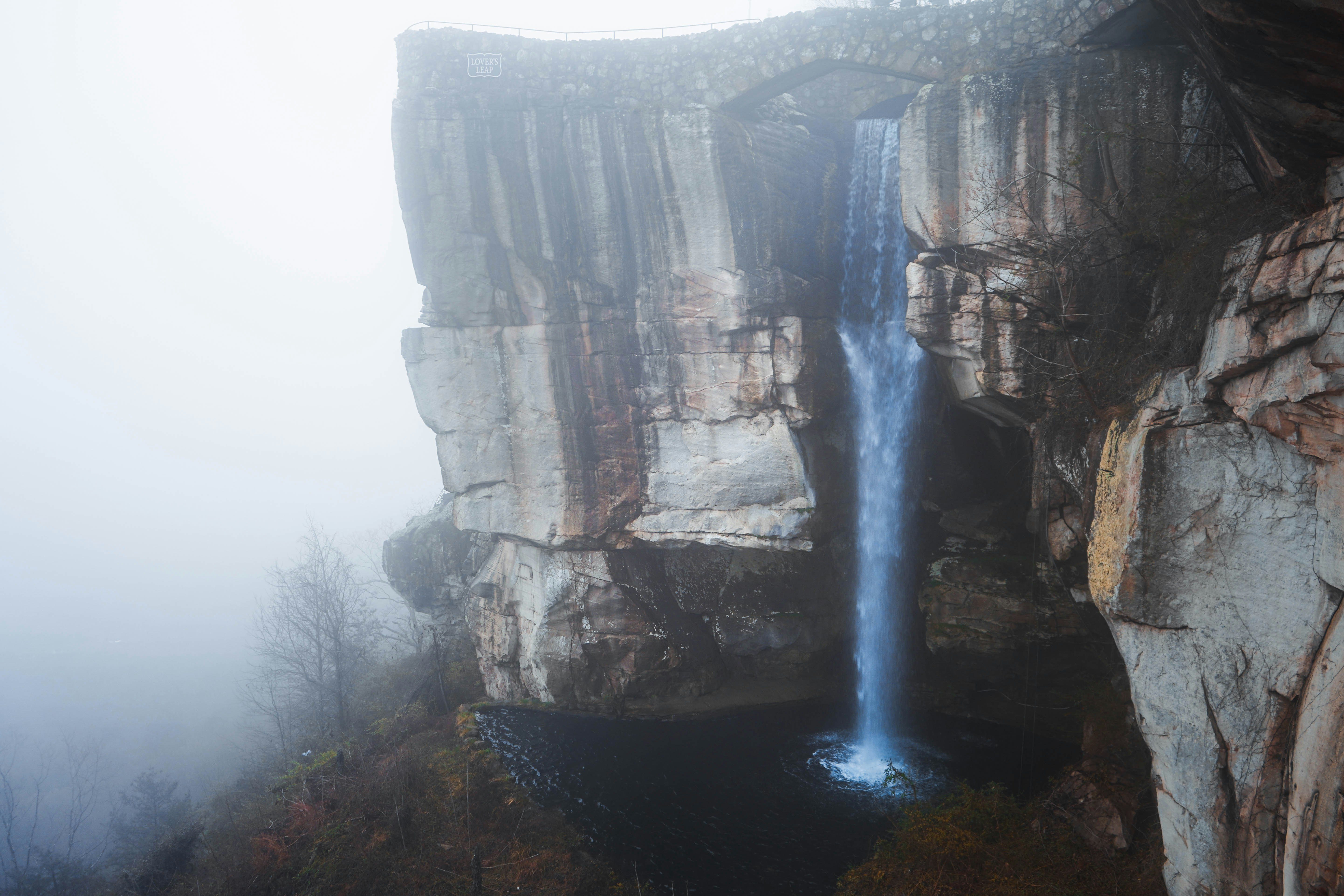 water falls between brown rocky mountain during daytime