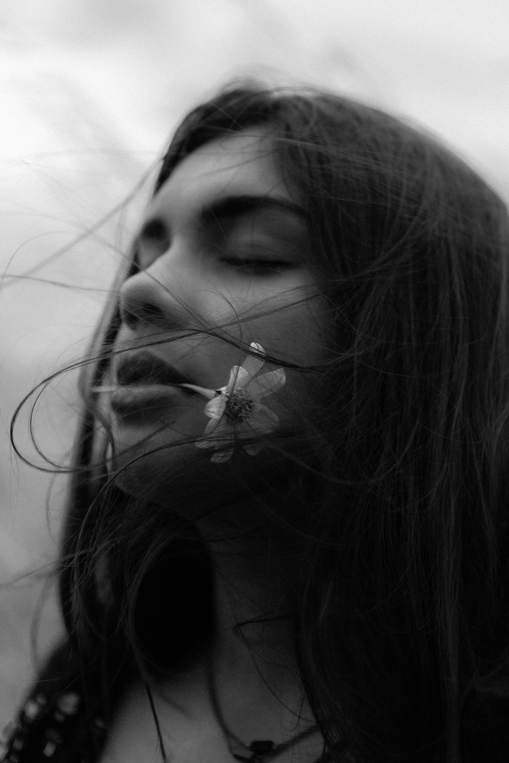 grayscale photo of woman with flower on her ear