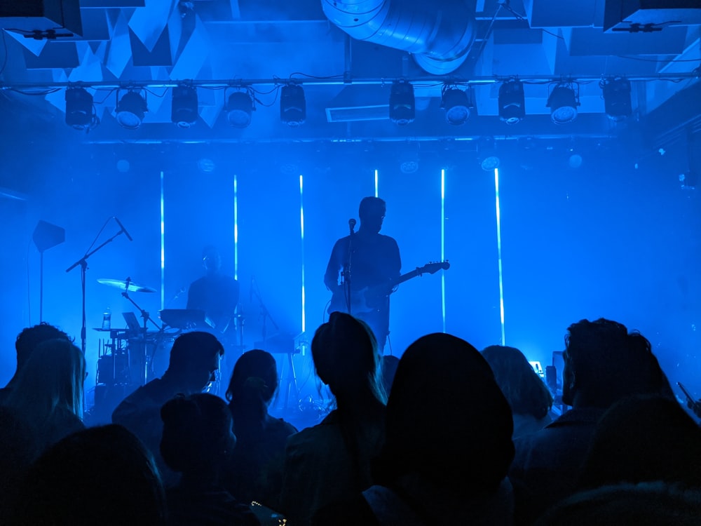 Hombre de camisa negra tocando la guitarra en el escenario