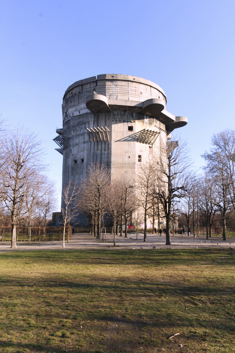 Braunes Betongebäude in der Nähe von kahlen Bäumen unter blauem Himmel tagsüber