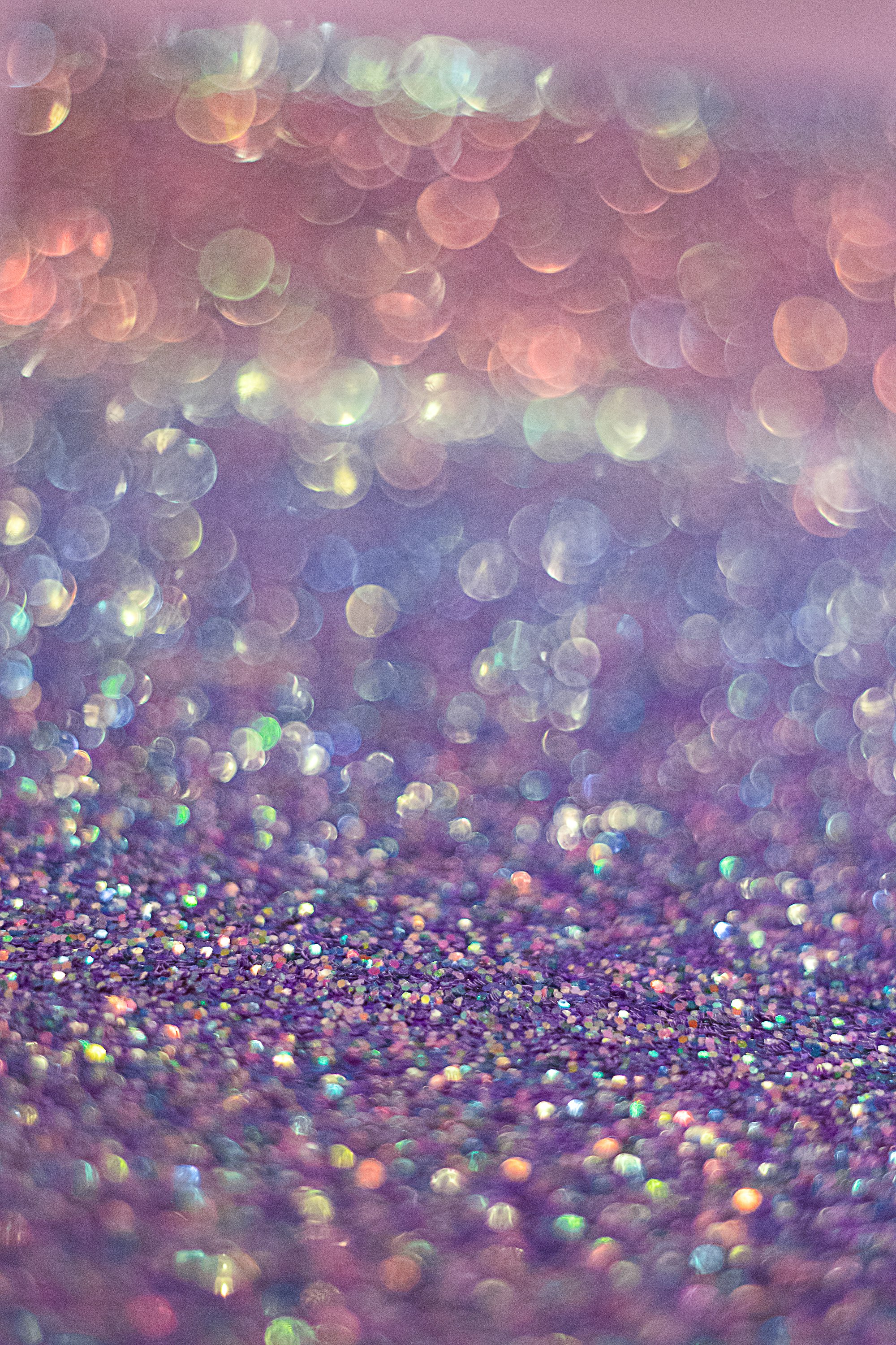 Closeup of purple and pink glitter surface with creamy boke background.