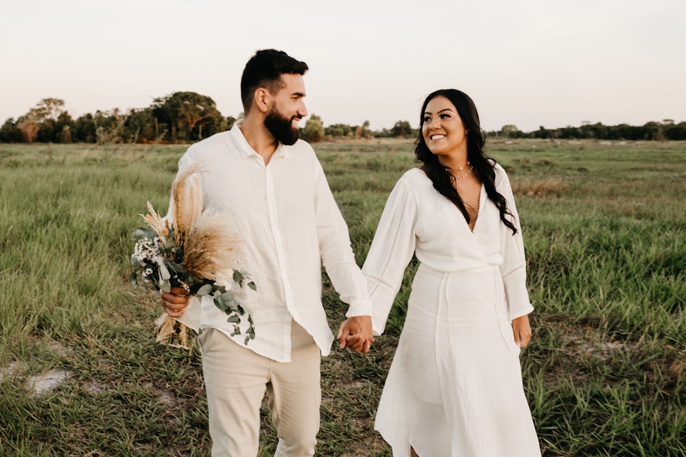 man and woman in white long sleeve shirt walking on green grass field during daytime