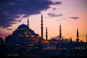 A serene mosque silhouette at dusk with models wearing sufiyaan’s modest luxury attire in the foreground