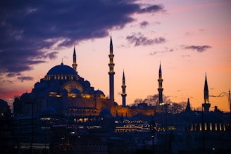 A serene mosque silhouette at dusk with models wearing sufiyaan’s modest luxury attire in the foreground
