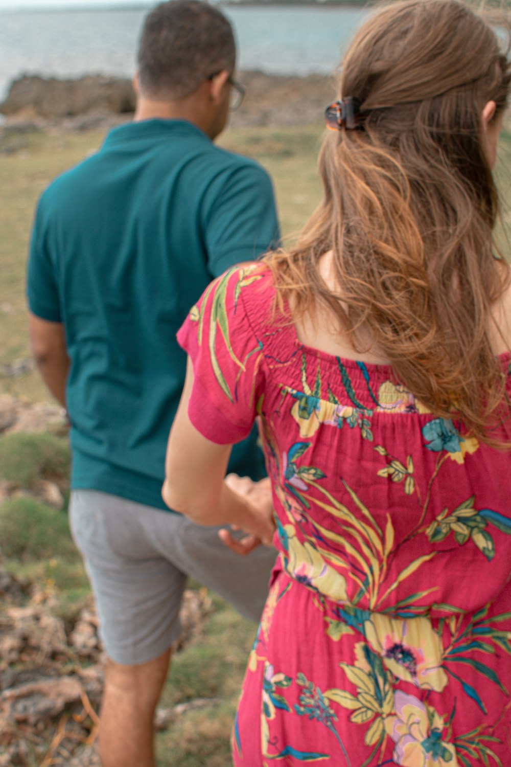 menina no vestido floral vermelho verde e azul que está ao lado do homem na camiseta azul