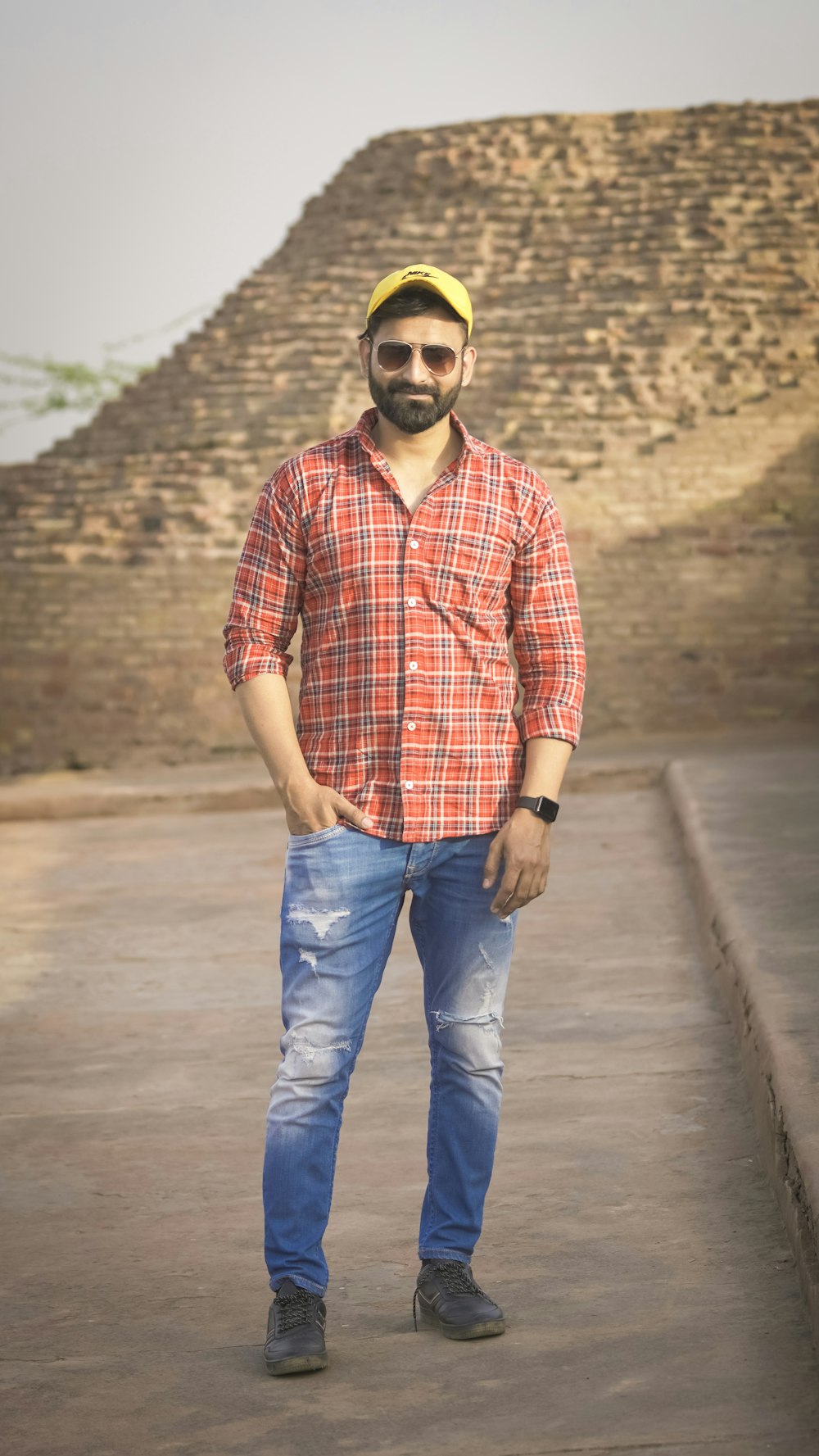 man in red and white plaid dress shirt and blue denim jeans standing on road during