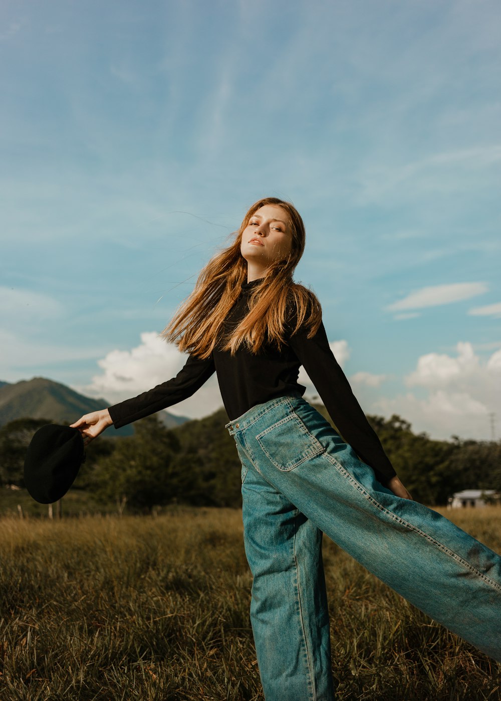 femme en chemise à manches longues noire et jean en jean bleu debout sur le champ d’herbe verte pendant