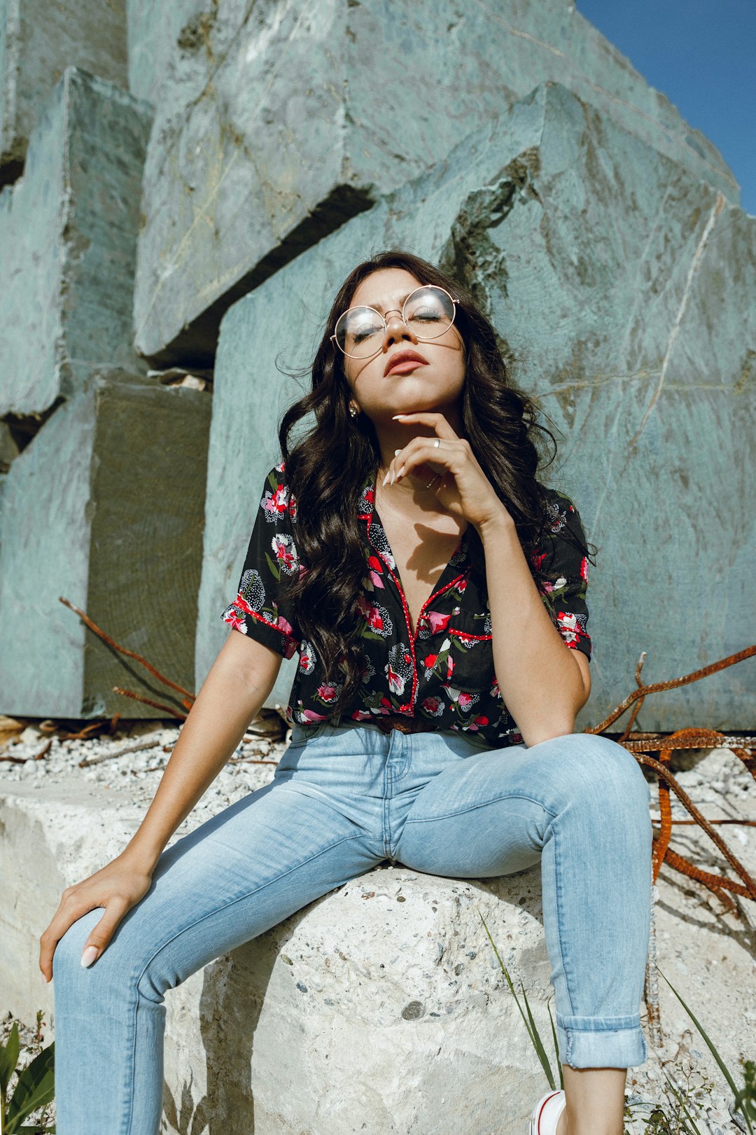 woman in blue denim jeans sitting on gray concrete wall