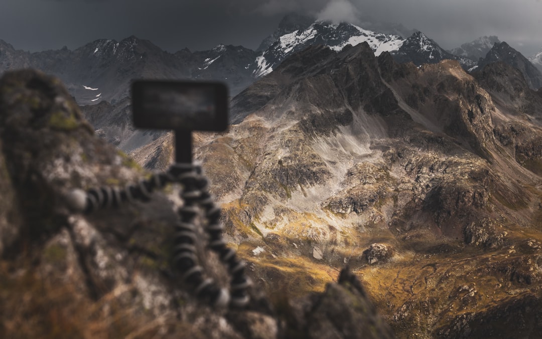 black wooden cross on brown grass field near mountain during daytime