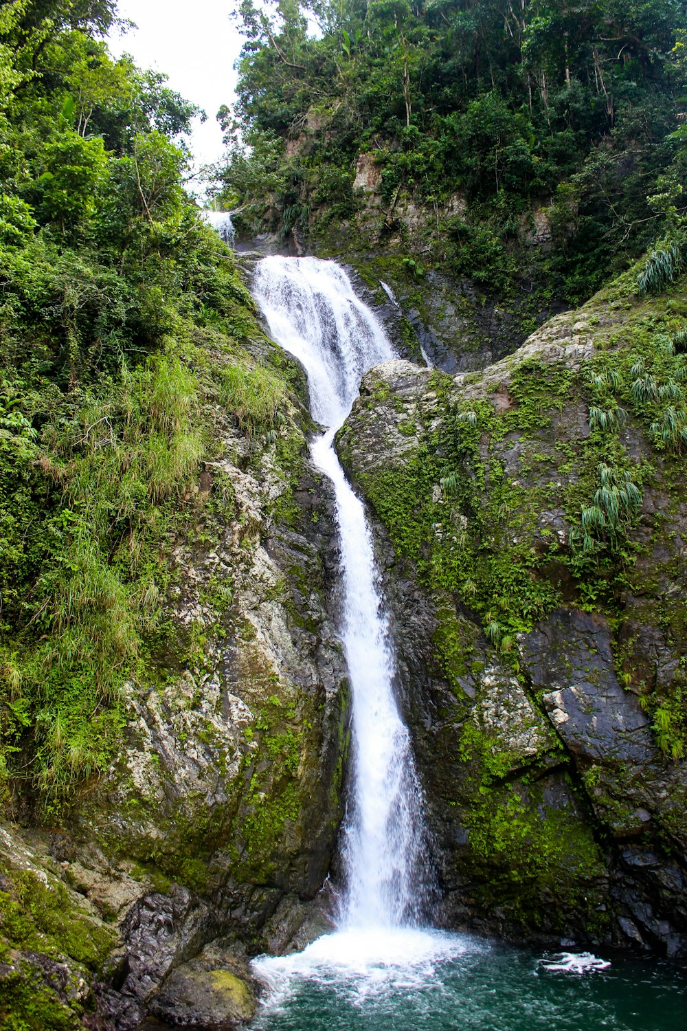 waterfalls in the middle of green grass covered mountain