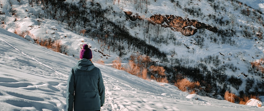 Persona in giacca nera in piedi su terreno coperto di neve durante il giorno