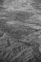 Aerial view of a sprawling wind farm with turbines arranged in neat rows across a vast landscape.