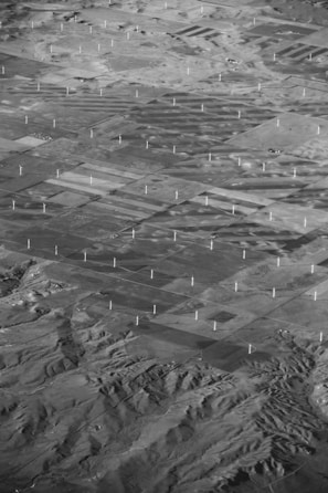 Aerial view of a sprawling wind farm with turbines arranged in neat rows across a vast landscape.