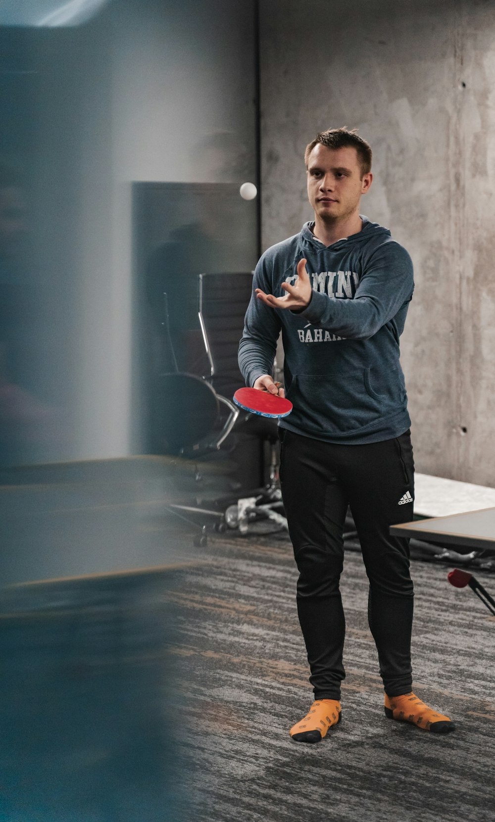 man in gray and black hoodie and black pants holding red and white basketball