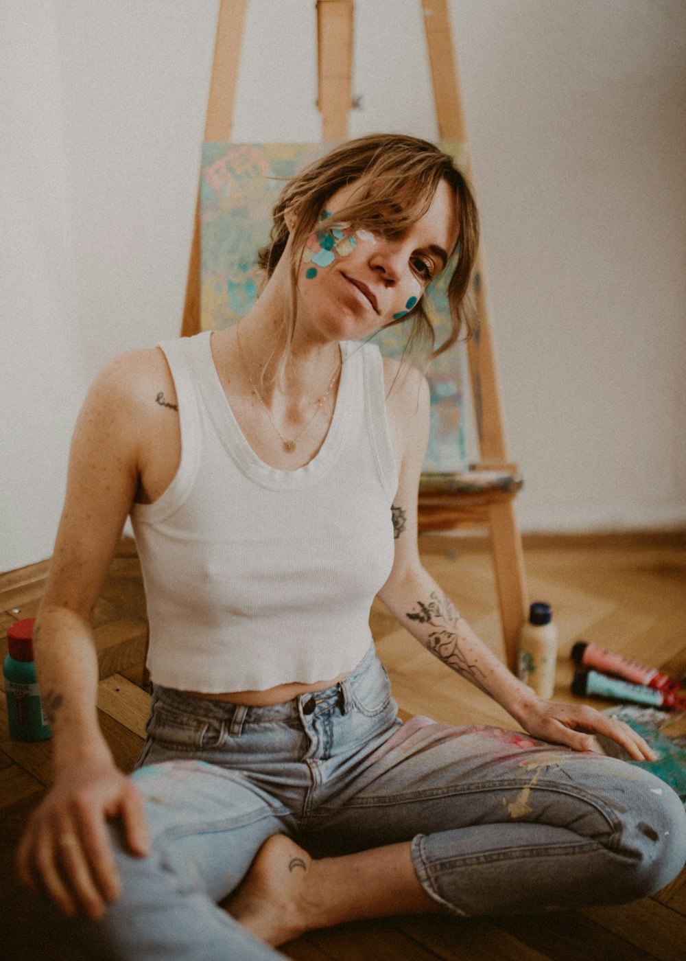 woman in white tank top and blue denim jeans sitting on bed