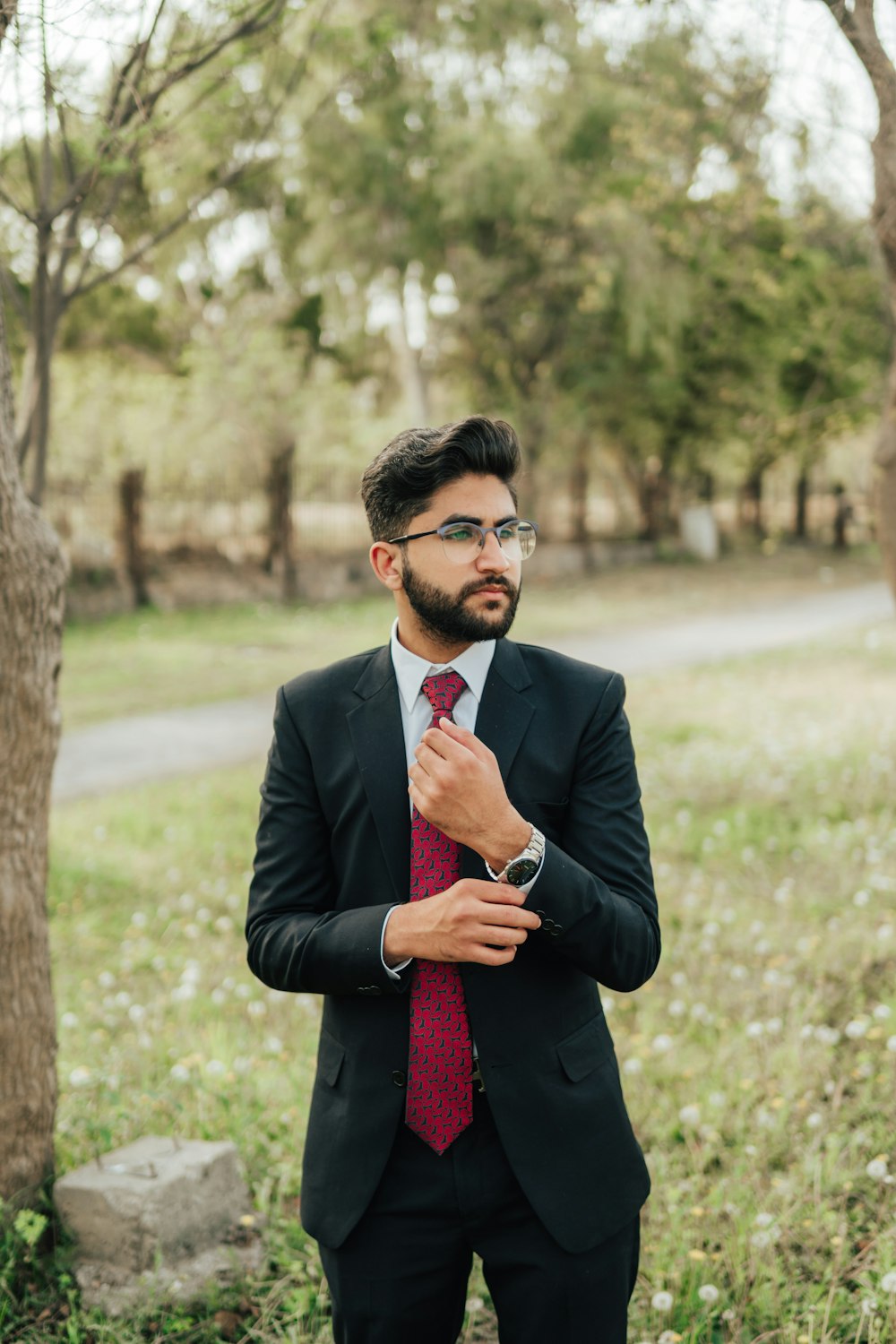 man in black suit jacket holding red necktie