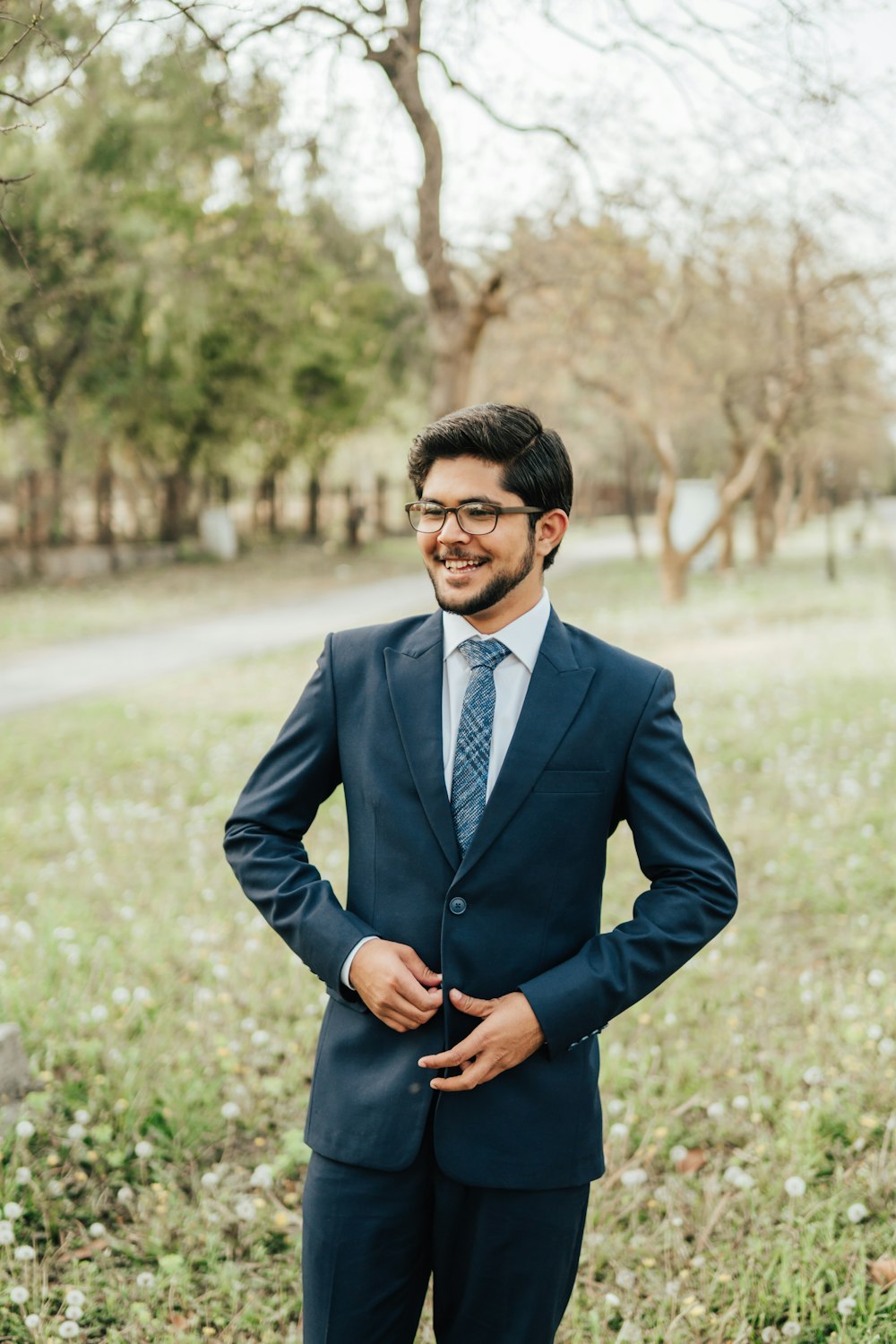 man in blue suit jacket and black dress pants standing on green grass field during daytime