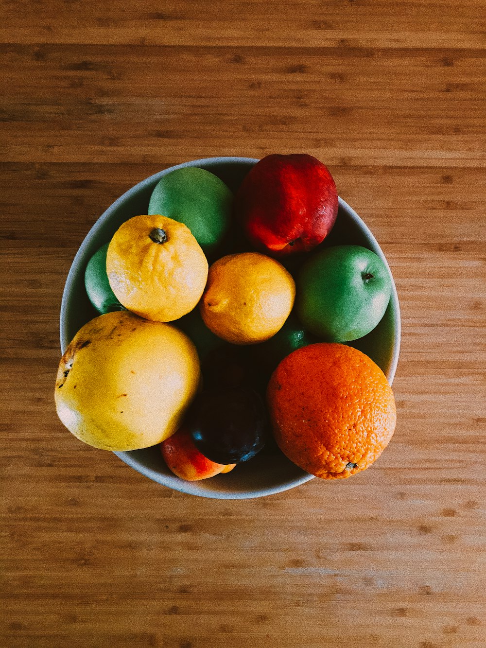 apple and orange fruits on white ceramic bowl