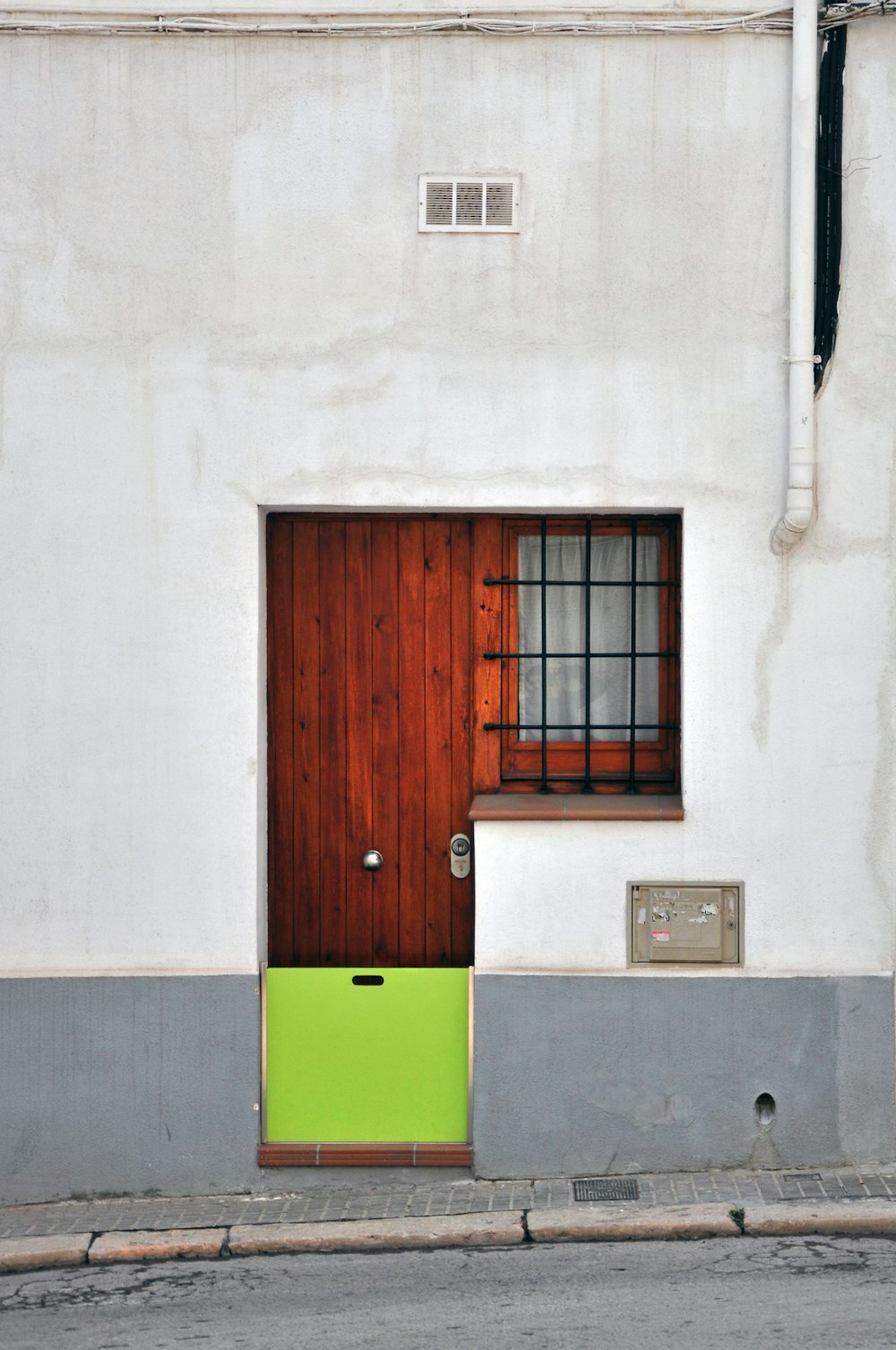 Puerta de madera marrón con felpudo verde y amarillo