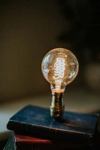 A stack of old philosophy and mathematics books with a glowing light bulb above them.