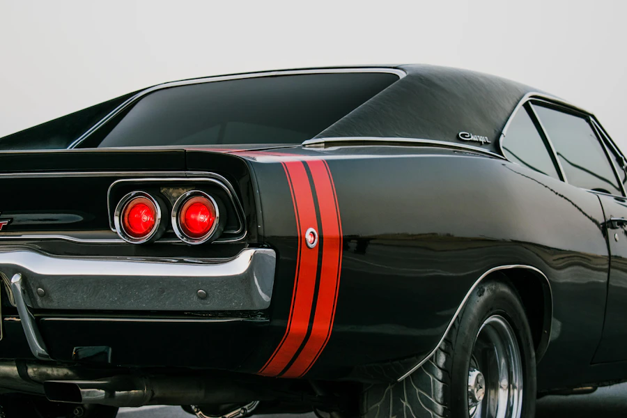 Rear three-quarter of a black American muscle car with a red tail stripe