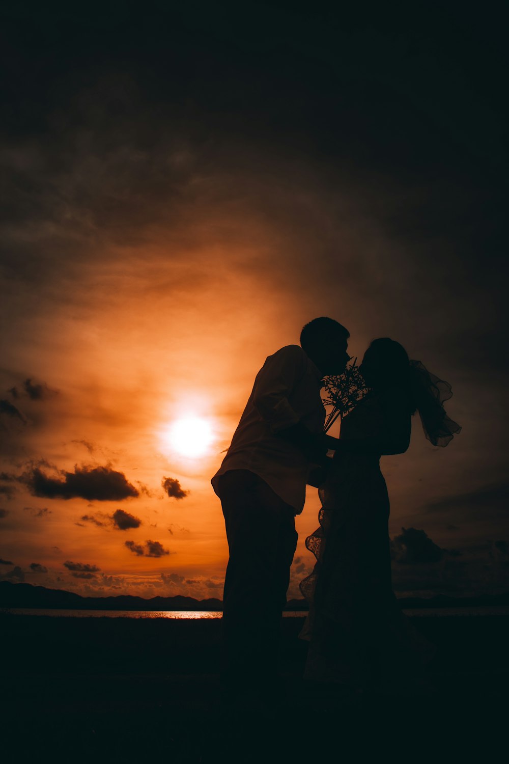 Silueta de hombre y mujer besándose durante la puesta del sol