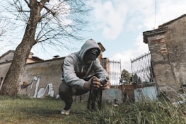 man in gray hoodie and black pants holding black and white labeled bottle