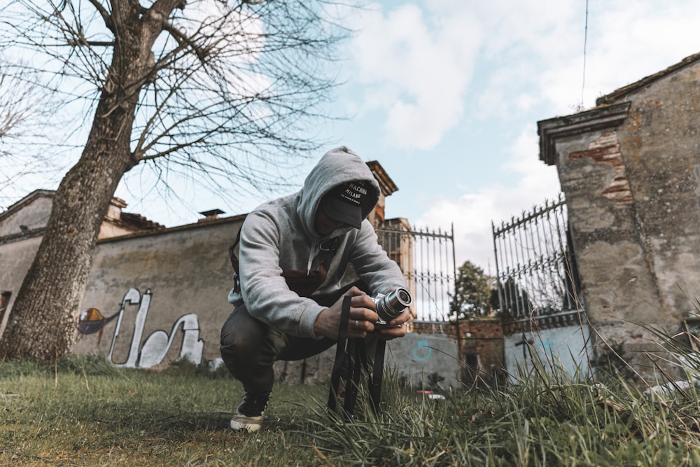 man in gray hoodie and black pants holding black and white labeled bottle