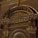An ornate architectural detail featuring intricate gold leaf designs and classical elements such as columns and arches. The decorations include floral motifs and symmetrical patterns, creating an elaborate and luxurious aesthetic.