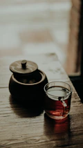 A rustic pu-erh tea cake resting on a wooden table beside a steaming cup, surrounded by soft morning light.