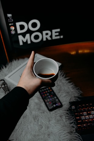 Close-up of hands holding a cup of coffee next to a laptop with productivity apps open.