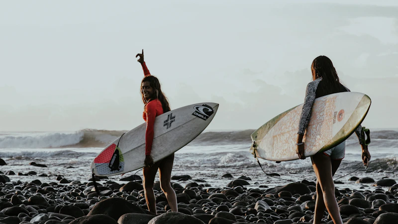 A surfer with her board on the rocky shore
