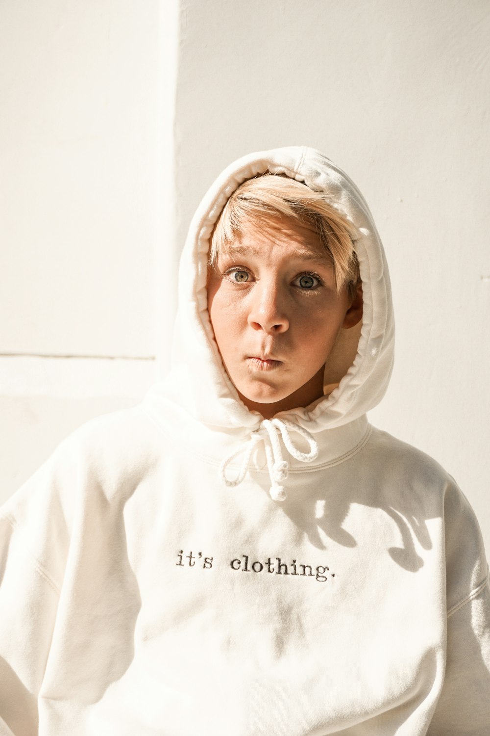 woman in white hoodie standing near white wall