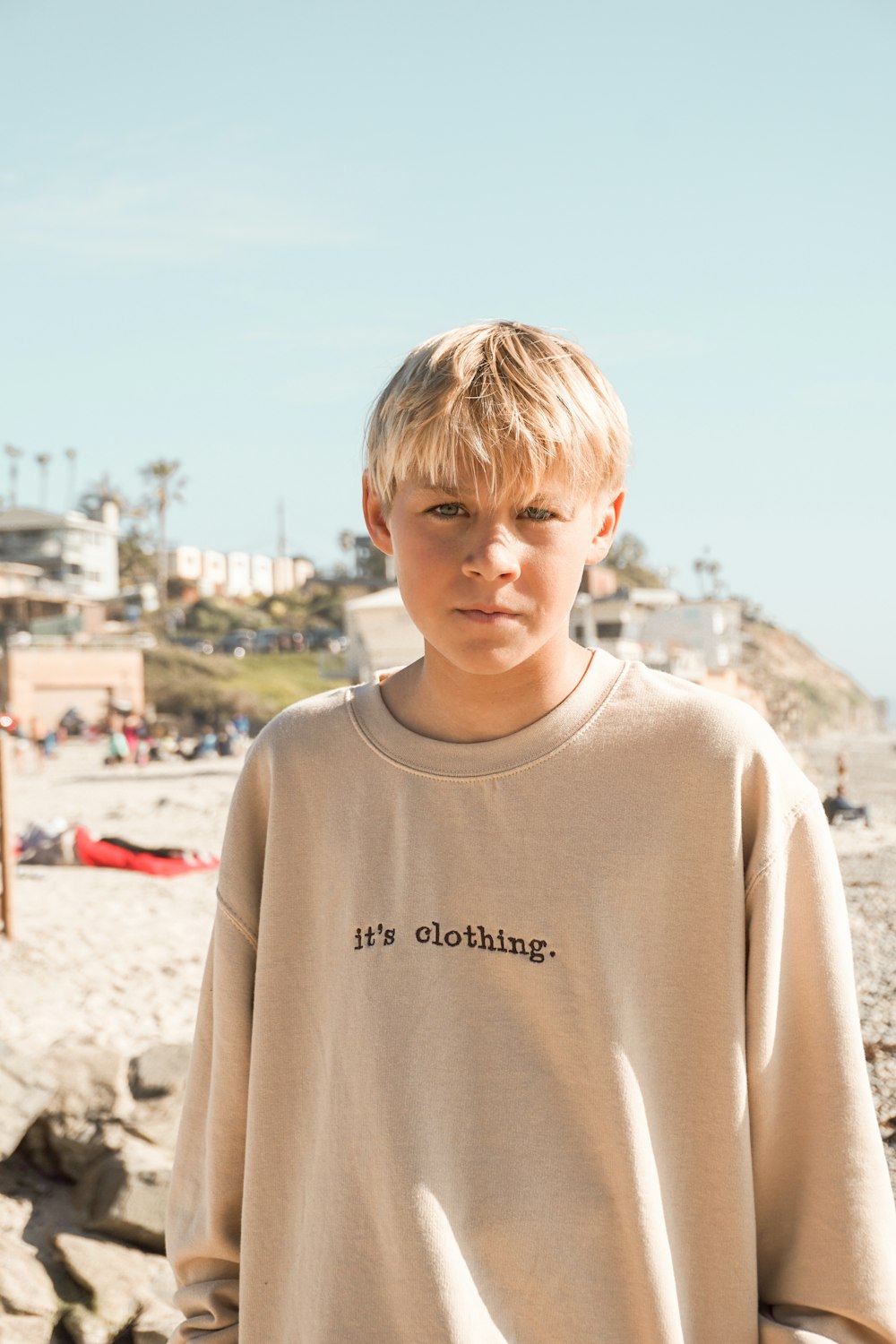 boy in white crew neck shirt standing on brown sand during daytime