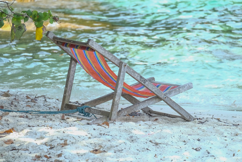 낮 동안 해변 해안에 빨간색과 파란색 줄무늬 접이식 의자