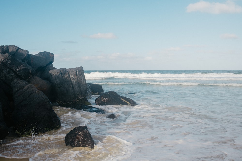 black rock formation on sea shore during daytime