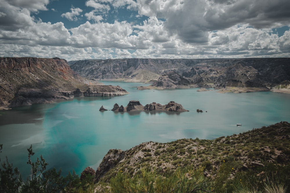 montaña verde y marrón junto al mar azul bajo nubes blancas y cielo azul durante el día