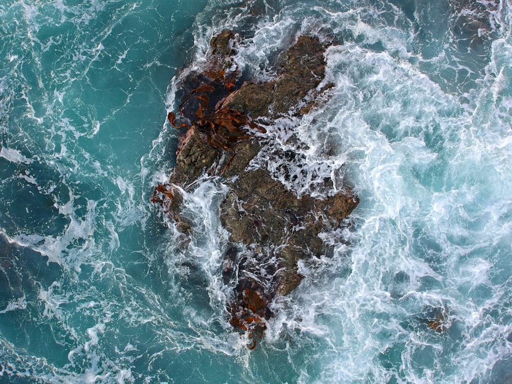 brown rock formation on body of water during daytime