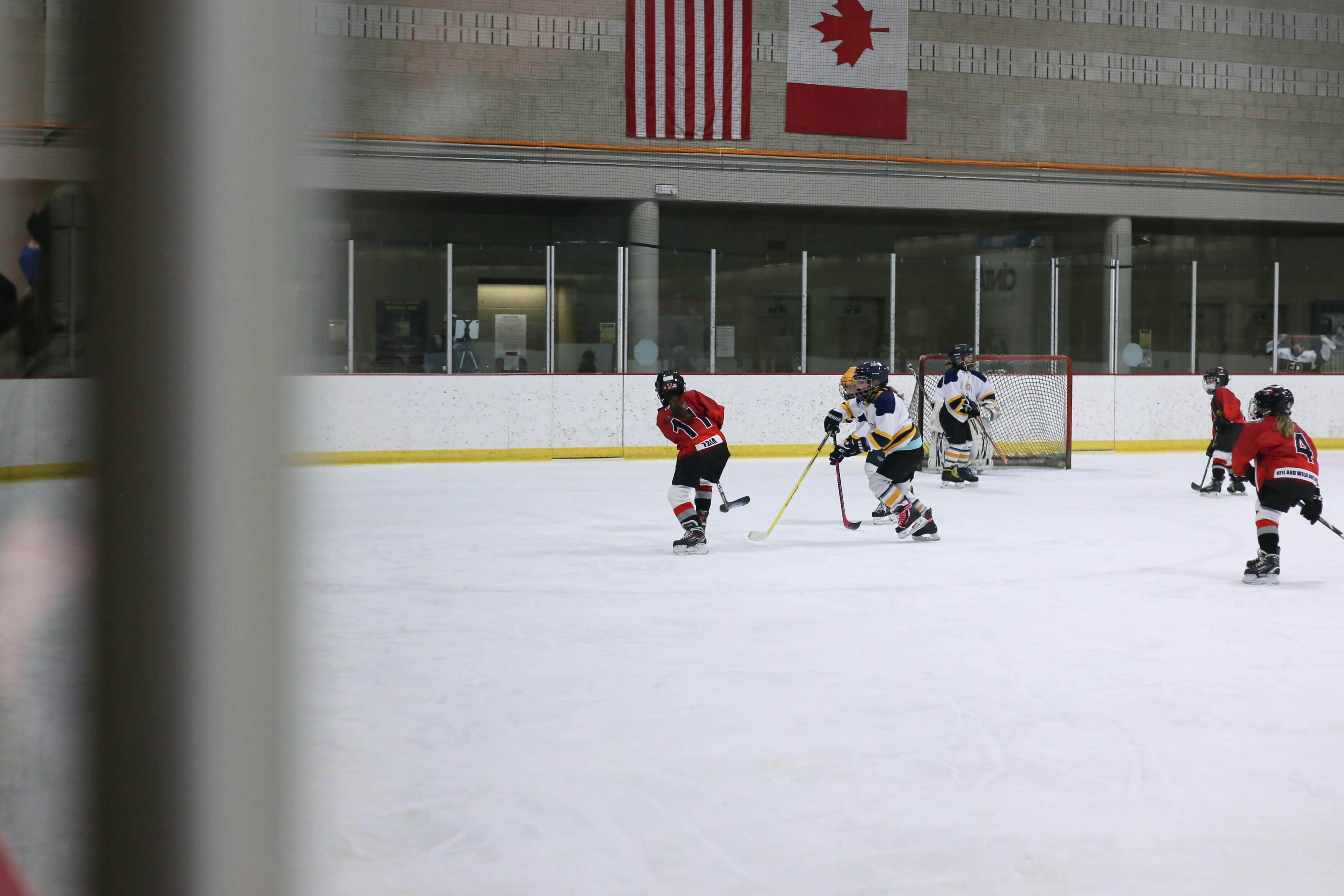 Parent québécois triant de l'équipement de hockey pour le donner à une autre famille, patinoire en arrière-plan