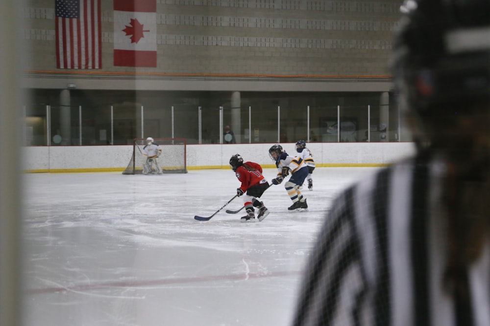 people playing ice hockey on ice field during daytime