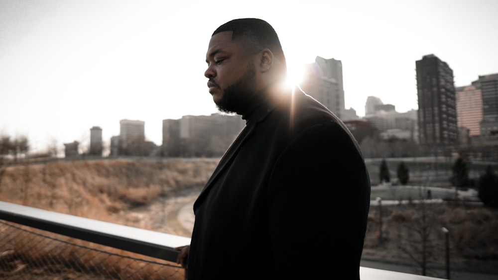 man in black coat standing near window during daytime