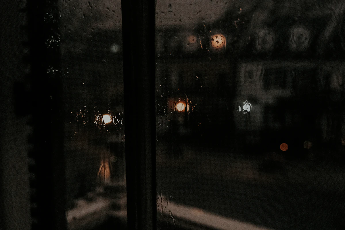 Gouttes de pluie sur une fenêtre et lumières floues de la ville le soir