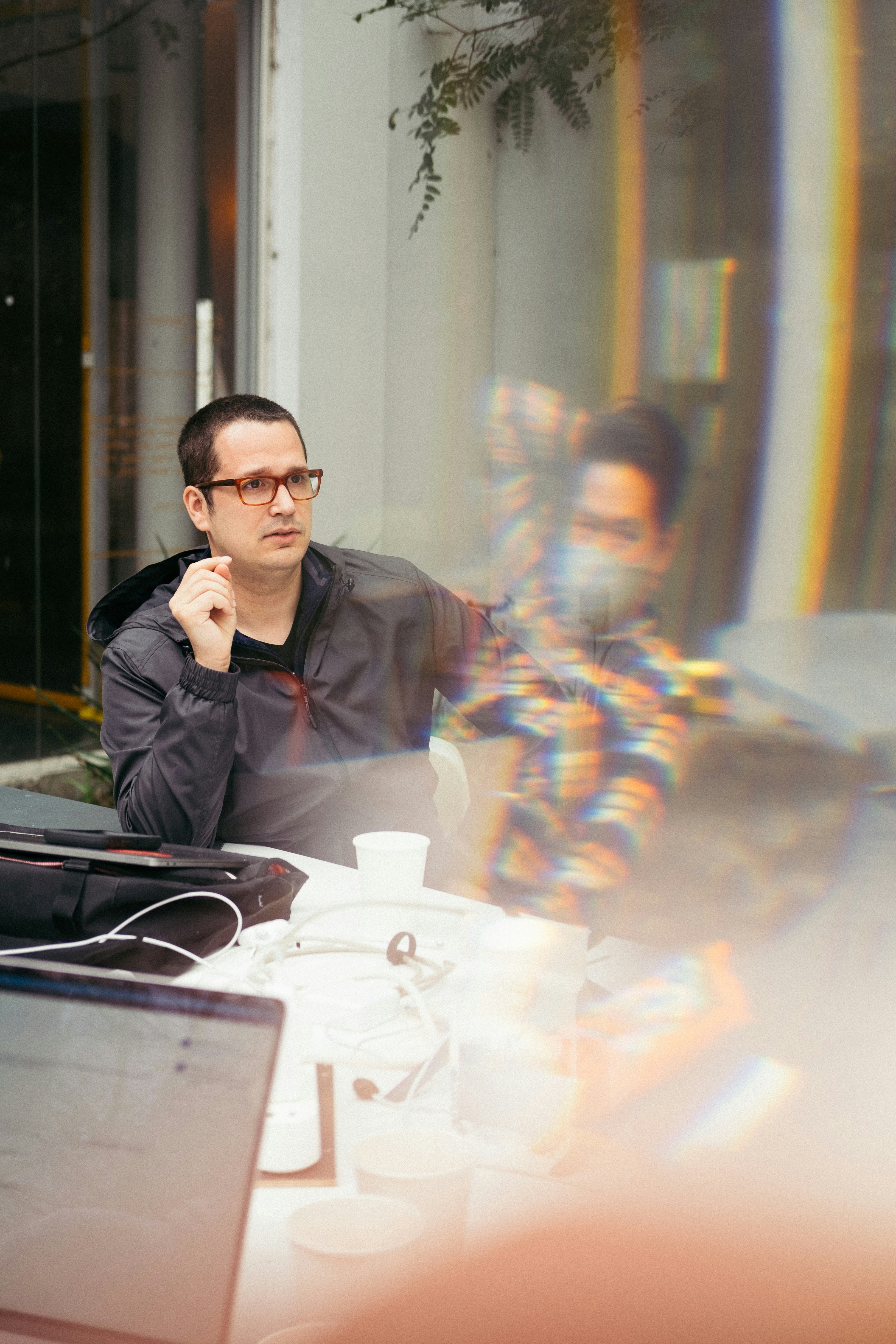 man in black jacket sitting beside table