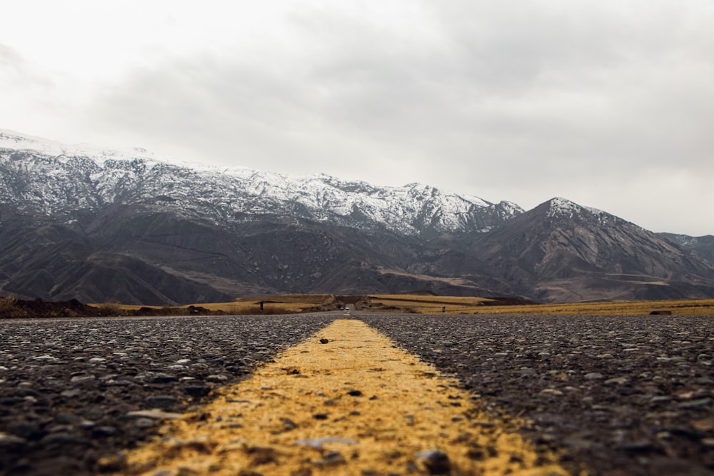 brown dirt road near snow covered mountain during daytime