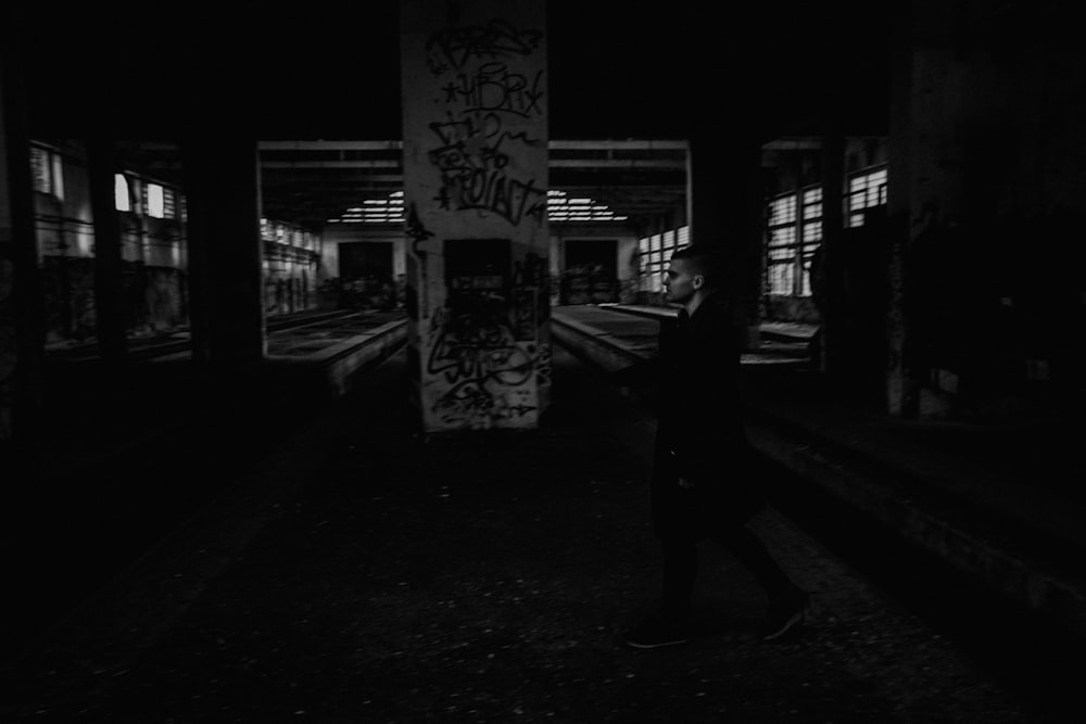 grayscale photo of man walking on street