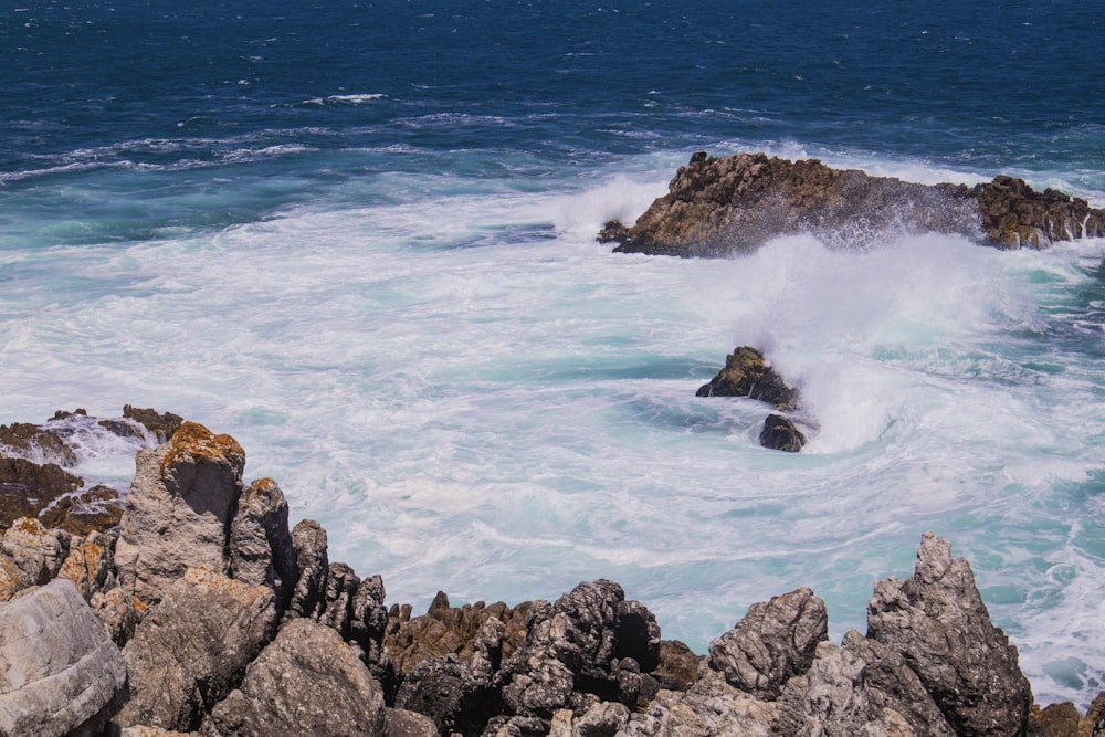 costa rochosa marrom com ondas do oceano durante o dia